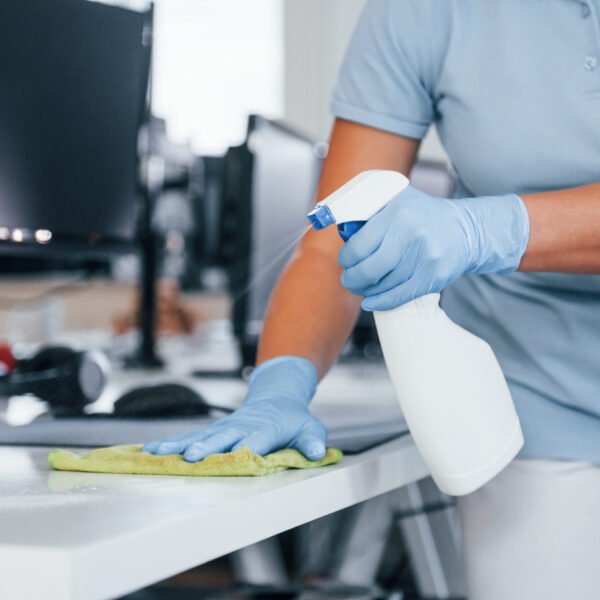 Close up view of woman in protective gloves that cleaning tables in the office.