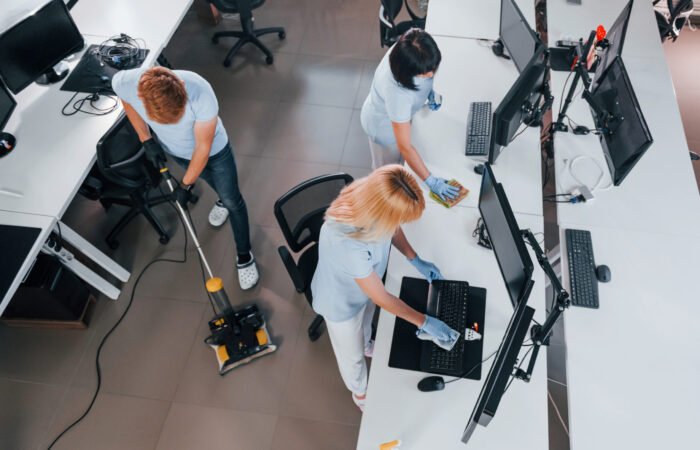Top view. Group of workers clean modern office together at daytime.